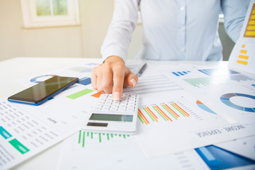 Businesswoman calculating income and balance using calculator.