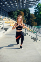 Young sporty woman doing exercises with rubber band outdoor