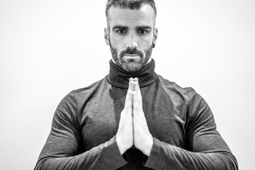 Portrait of a young muscular Caucasian man with yoga prayer pose, black and white photo