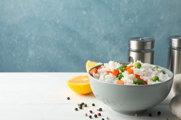 Composition with bowl of delicious rice on wooden table, space for text