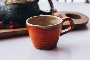 tea pot and orange cup on window background with flowers