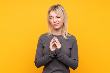 Young blonde woman over isolated yellow background scheming something