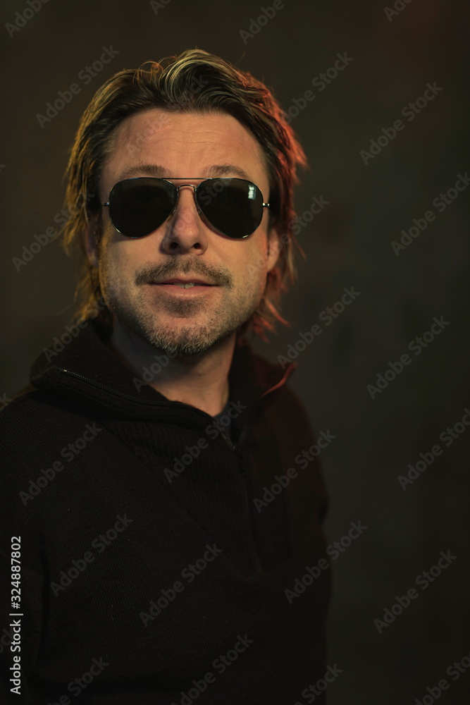 Wall mural man wearing dark sunglasses and a black woolen sweater.