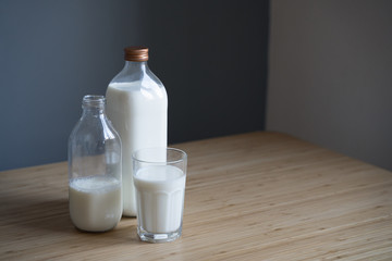 bottles of milk and glass on light colored wooden table