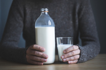 young man in dark wool sweater keeping a glass of milk in his hand