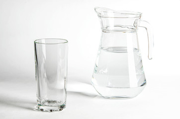 Pure clear water in a glass and jug stands on a white background