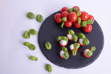 basil is scattered on the table and tomatoes on a stone tile