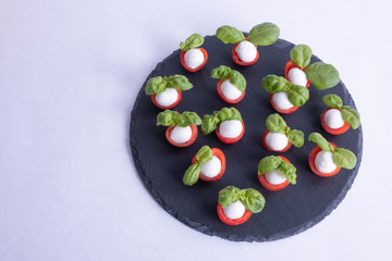 basil lies on tomatoes on a stone black tile