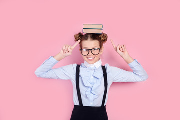 Funny schoolgirl with books on her head, wearing glasses and school uniform
