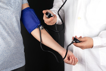 the doctor measures the pressure of the patient. sphygmomanometer