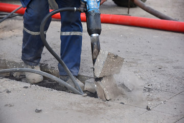 Construction worker with a pneumatic hammer, conducts road works.
