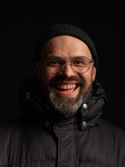 Portrait of a man in a hooded jacket. Studio shooting, dark background.