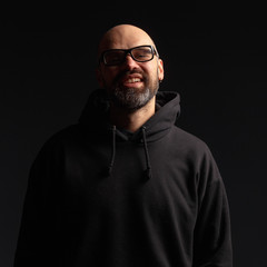 Obraz premium Portrait of a man in a hooded jacket. Studio shooting, dark background.