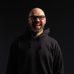 Portrait of a man in a hooded jacket. Studio shooting, dark background.