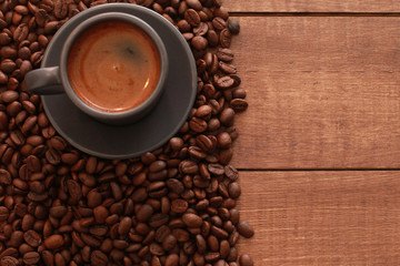 Grey cup of coffee with foam, roasted beans on brown wooden table. Closeup, copy space, top view. Coffee shop, espresso, fresh roast, drink  concept