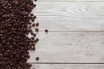 Natural coffee beans  on white wooden table. Dark roasted beans for espresso. Natural ingredient, agriculture, coffee shop, backdrop concept