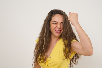 Fototapeta na wymiar Fierce confident European dark-haired woman holding fist in front of her as if is ready for fight or challenge, screaming and having aggressive expression on face. Isolated over gray background.