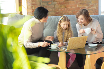 Comfortable. Happy loving family. Grandmother, mother and daughter spending time together. Watching cinema, using laptop, laughting. Mother's day, celebration, weekend, holiday and childhood concept.