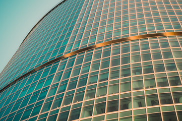 part of modern glass skyscraper in the morning light. Perspective view of commercial building on th background of clear blue sky.