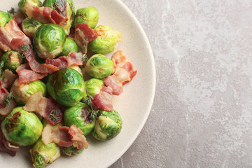 Delicious Brussels sprouts with bacon on marble table, top view. Space for text