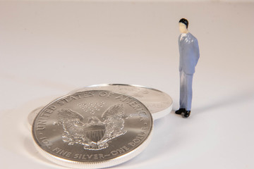 Male miniature figure standing beside US silver eagle coins