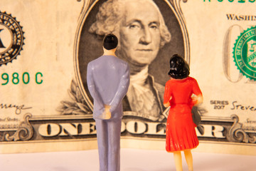 Miniature figure male and female gazing at a dollar bill