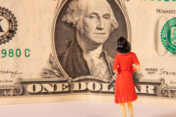Female miniature figure gazing at a US dollar bill
