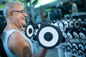 Uomo anziano fa degli esercizi con i pesi in palestra