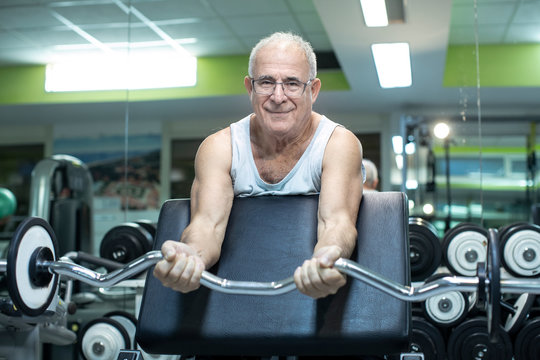 Uomo anziano fa degli esercizi con i pesi in palestra