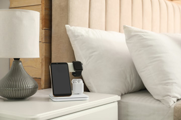 Different gadgets charging on wireless pad in bedroom