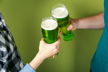 Man and woman toasting with green beer on color background, closeup. St. Patrick's Day celebration