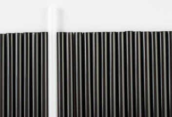 Black and white straws for drinks. The white object stands out against the black objects.