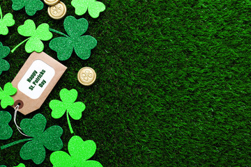 Flat lay composition with clover leaves and gold coins on green grass, space for text. St....