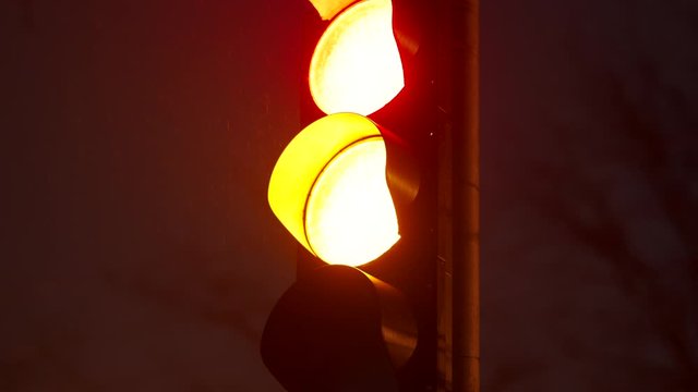 Red yellow green traffic light at night city street closeup.