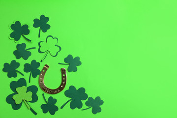 Flat lay composition with clover leaves and horseshoe on green background, space for text. St....