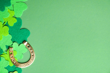 Flat lay composition with clover leaves and horseshoe on green background, space for text. St....