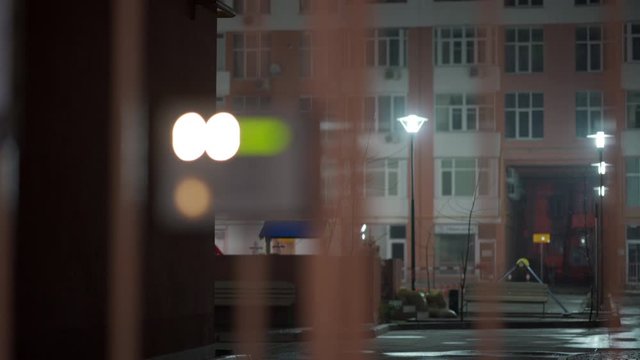 Safety in modern residential building, fenced yard, closed gate with electronic lock and intercom at night, rack focus.