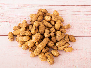 Fototapeta premium peanuts in the skin and peanuts without the skin in a wooden plate on a wooden table
