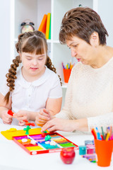 Girl with Down Syndrome works with her teacher at home