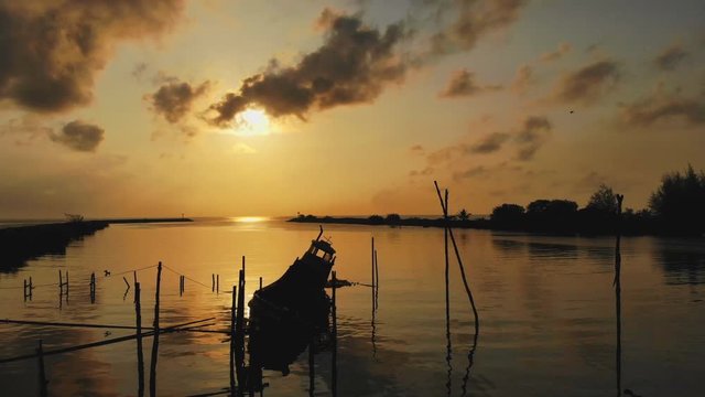 The beauty of An old fishing boat moored up in the morning sunlight aerial view sunrise. Royalty high quality free stock footage, Silhouette Scene of Fishing Boat on Beach with Golden Sunlight in the 