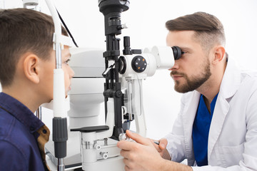 Experienced doctor checks the eyesight of a teenage boy. Modern clinic for checking and treating...