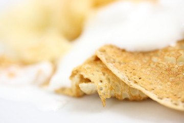 A pancake with a golden crust poured sour cream