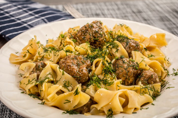 Tagliatelle pasta with pork meatballs and dill sauce. Selective focus.