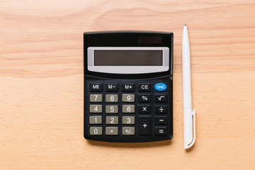 Accounting, financial concept, flat lay, calculator and pen on wooden table