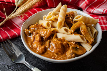 Penne pasta in pork sauce with mushroom.