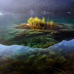 Scenic image of fairy-tale Fusine lake with calm clear water under sunlit. Wonderful Autumn scenery. Picturesque view of nature. Amazing natural Background. Incredible view on Fusine lakeside
