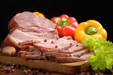 Smoked meat sliced on a wooden table with the addition of fresh herbs, aromatic spices and paprika. A natural product from an organic farm produced using traditional methods.
