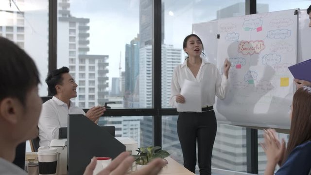 Young asian business woman presenting data idea marketing on board in office. Asia woman show mind mapping and ideas to business partner or colleagues group enjoy teamwork in small office