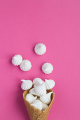 Ice cream cone with white meringue  in the center of the pink background. Top view. Copy space. Location vertical.