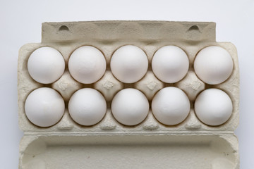 Cardboard egg box with ten eggs isolated on white. Front view.